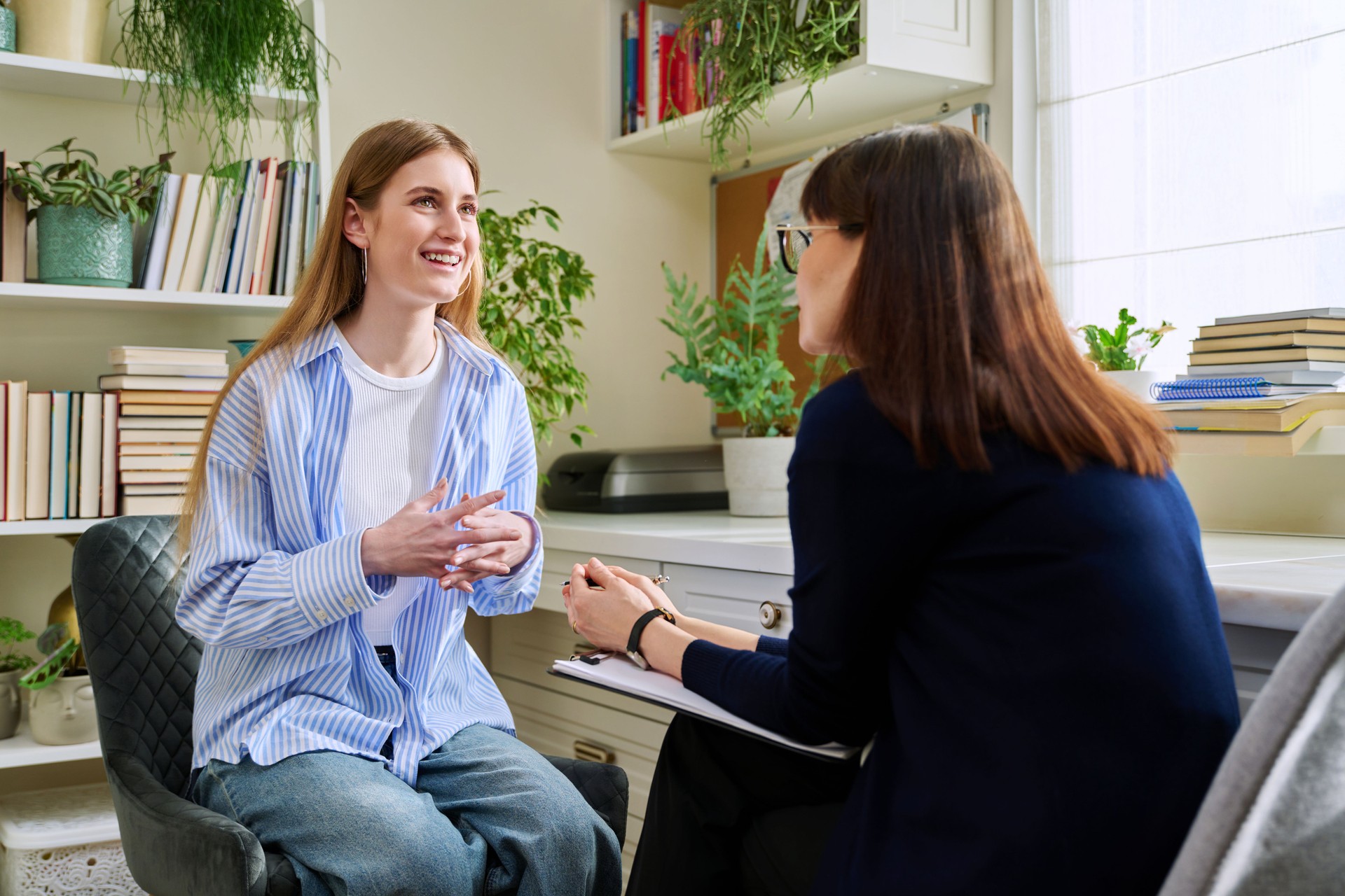 Smiling young teenage female patient talking to professional mental therapist Smiling young teenage female patient talking to professional mental therapist